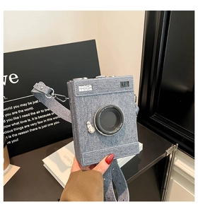 Detail of light blue denim vintage camera shaped crossbody bag with realistic lens design