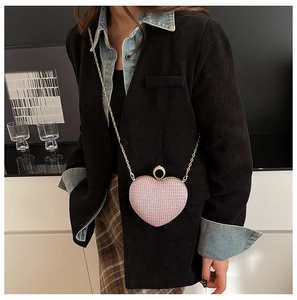 Détail d'une pochette rose pailletée en forme de cœur avec fermoir anneau doré et strass