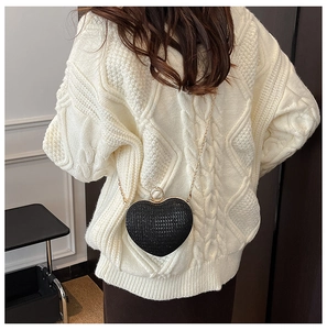 Détail d'un sac de soirée noir en forme de cœur avec strass et chaîne dorée fine