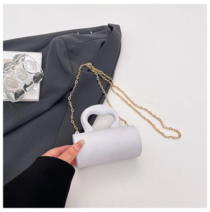 Gros plan d'un sac de soirée cylindrique blanc avec poignée nuage et chaîne dorée