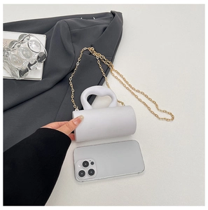 Mini sac cylindrique blanc à côté d'un smartphone montrant sa taille compacte