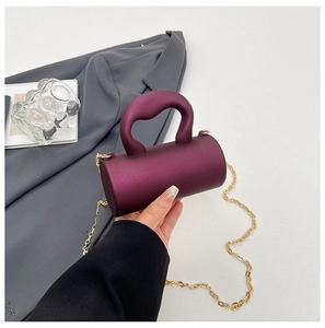 Détail du sac cylindrique en acrylique violet avec poignée épaisse et chaîne dorée