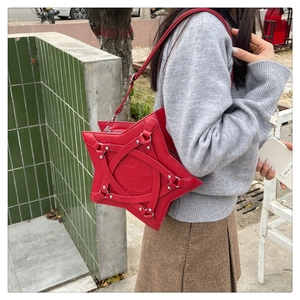 Outdoor shot of a red star-shaped crossbody bag with silver rivets and star embossing