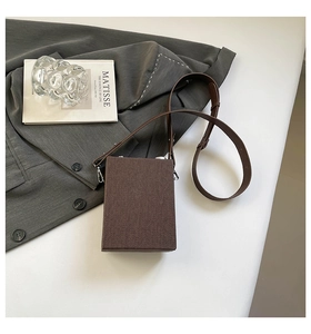 Detail of vintage brown camera box bag with leather strap on a stylish grey blazer