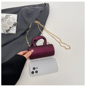 Mini sac capsule violet en acrylique avec chaîne dorée présenté à côté d'un mobile