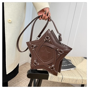 Detail of star-shaped brown leather shoulder bag with metallic rivets and cross straps