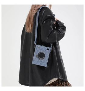 Detail of blue camera-shaped crossbody bag made of denim texture with metallic accents