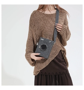 Macro detail of a gray vintage camera-shaped crossbody bag with a simulated lens design