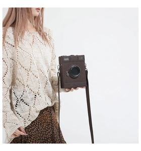 Detail of retro camera-shaped crossbody bag in dark brown with textured faux leather