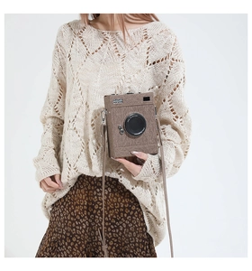 Retro camera-shaped crossbody bag shown on model with textured fabric and vintage lens detail