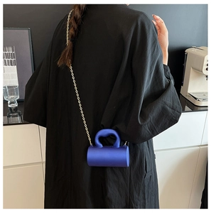 Détail du mini sac cylindre bleu marine avec une élégante bandoulière chaîne dorée
