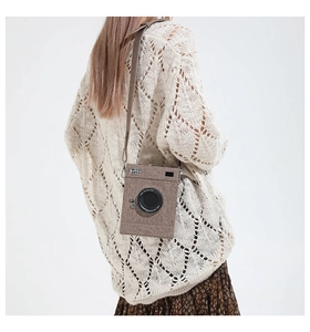 Macro view of vintage-style camera-shaped crossbody bag with textured fabric and leather strap