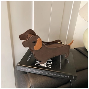 Detail view of the brown leather dachshund-shaped bag resting on a decorative book
