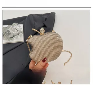 Detail of apple-shaped evening clutch with gold glitter finish and rhinestone leaf
