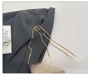 Detailed close-up of premium gold metallic chain strap on a woven acrylic evening clutch bag