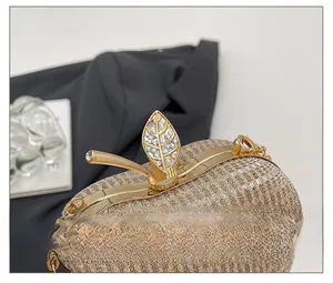 Detail showing the apple leaf clasp with white rhinestones on a gold evening bag