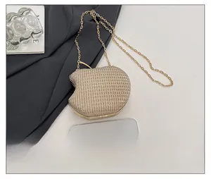 Detail of apple-shaped evening bag featuring gold rhinestones and metal chain strap