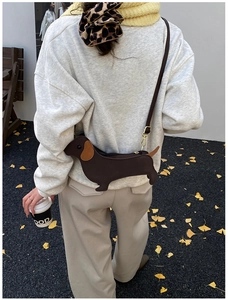 Detail of creative dachshund animal-shaped shoulder bag with adjustable brown leather strap