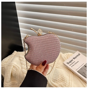 Detail of pink glitter apple-shaped clutch bag with golden leaf clasp and chain strap