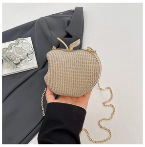 Close-up of golden apple-shaped evening clutch with leaf clasp and metal chain