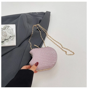 Detail of pink apple-shaped clutch with glitter texture and gold chain strap