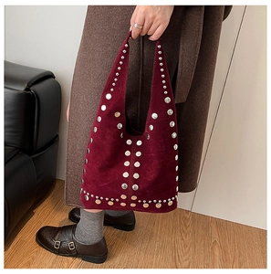 Dettaglio della borsa tote bordeaux in pelle scamosciata con borchie argentate e manico largo