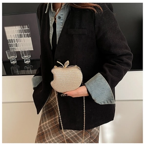 Detail of apple-shaped champagne gold evening clutch with glitter texture and leaf clasp