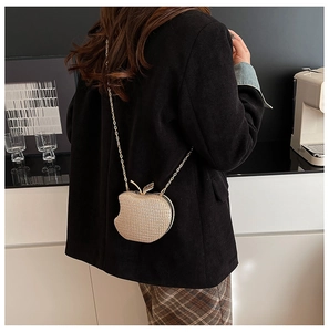 Close-up of golden sequin apple-shaped crossbody bag with metal chain and leaf detail