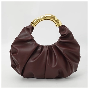 Detail of wine red pleated handbag with curved golden wave-textured metal handle