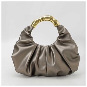 Detail of metallic gold pleated dumpling bag with elegant curved metal handle