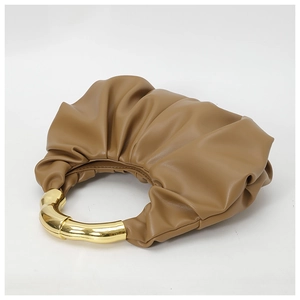 Detail of caramel pleated cloud bag featuring a structured gold metal handle and soft leather