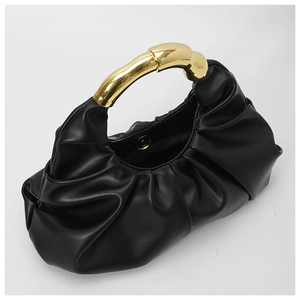 Close-up of black ruched handbag featuring an artistic curved golden metal handle