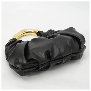 Detail of a black ruched cloud bag featuring elegant gold circular metal handles