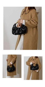 Detail of black pleated cloud bag featuring elegant round gold metal handles for women