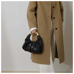 Detail of black pleated hobo bag featuring a distinctive gold-toned metallic handle