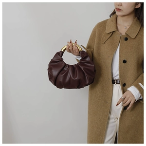 Detail of dark brown ruched cloud bag featuring a stylish gold circular metal handle