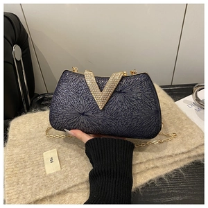 Detail of dark blue evening clutch with radial texture and crystal V-shape closure