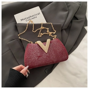 Close-up of burgundy evening clutch with sparkling V-shaped rhinestone buckle and gold chain