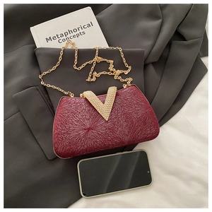 Detail of wine red evening bag with V-shaped crystal clasp and golden metal chain strap