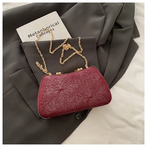 Detail view of burgundy evening bag with sparkling starburst texture and gold chain strap