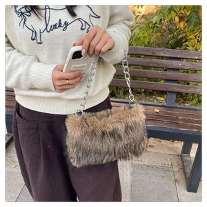 Détail d'un sac en fausse fourrure avec bandoulière chaîne argentée sur un banc