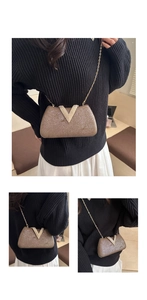 Close-up of brown textured evening bag with gold V-shape buckle and chain strap detail