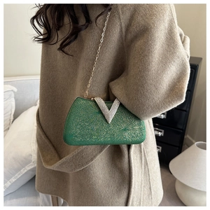 Detail of emerald green box clutch with gold pattern, V-logo buckle and chain strap