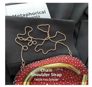 Detail shot of a red rhinestone clutch bag with gold metal frame and elegant chain strap