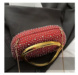 Detail of red evening clutch featuring silver studs and a gold oval metal handle