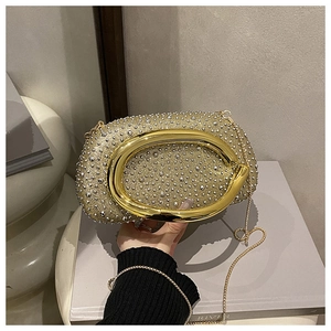 Detail einer goldenen Abendtasche mit glitzernden Strasssteinen und ovalem Metallgriff