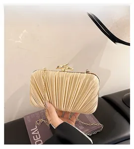 Detail of champagne gold pleated clutch with silk texture and bamboo metal clasp
