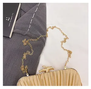 Detail of gold satin pleated evening bag with elegant metal bamboo clasp and chain strap