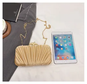 Gold pleated evening bag shown next to a tablet for size comparison and capacity reference