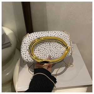 Detail der weißen Abendtasche mit Strasssteinen und großem goldenen Metallrundgriff